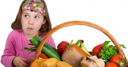 Gesunde Ernährung bei Kindern, Mädchen sitzt vor Obst/Gemüse Korb